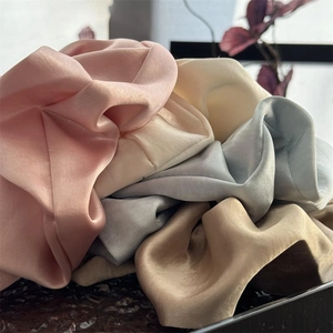Detailaufnahme von Premium-Satin-Scrunchies in Champagner und Pastellfarben mit Seidenglanz