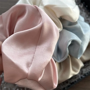 Makro-Detail von Satin-Haargummis in Pastellfarben mit glänzend plissierter Textur