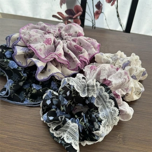 Dettaglio di elastici scrunchie floreali blu e viola con delicato bordo in pizzo