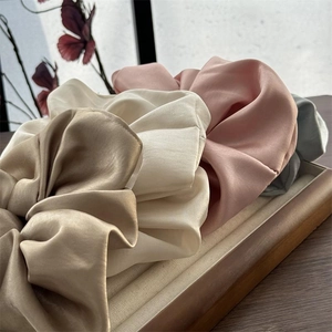 Detailansicht von Satin-Haargummis in Champagner-Farbe auf einem Holztablett