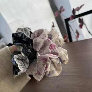 Dettaglio degli elastici scrunchies floreali in pizzo sul polso con tessuto e ricami
