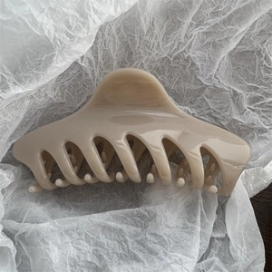 Detail view of large cream hair claw clip with smooth finish on white textured paper