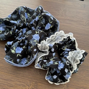 Dettaglio di elastici scrunchie con rose blu e pizzo bianco su base di legno
