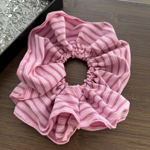 Close-up of pink striped scrunchie made of soft cotton fabric with rich elastic folds