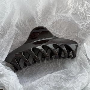 Detailed view of glossy 14cm large hair claw clip on elegant white paper