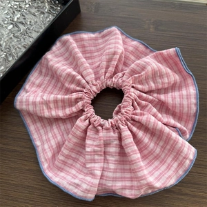Close-up of pink and white checkered scrunchie with blue edging on a wooden table