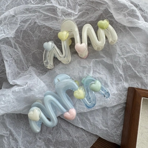 Detail von creme-weißen und blauen Wellen-Haarklammern mit bunten Herz-Akzenten