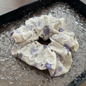 Dettaglio dell'elastico floreale con rose viola e bordo in pizzo bianco fine