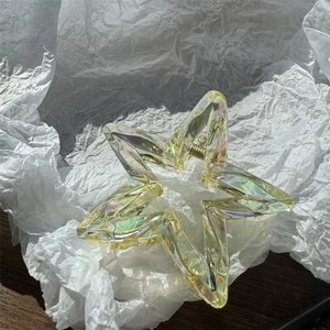 Détail du clip à cheveux en forme d'étoile irisée sur fond de papier blanc froissé