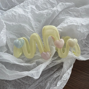 Detail der wellenförmigen Haarklammer in Pastellgelb mit bunten kleinen Herzen