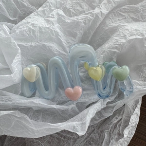 Detailansicht der gewellten cremeblauen Haarklammer mit bunten 3D-Herz-Dekorationen
