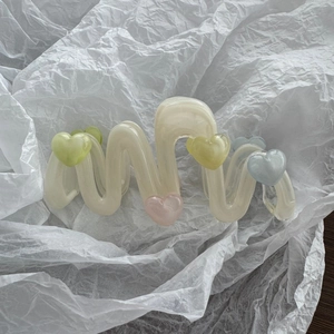 Nahaufnahme der cremefarbenen Haarspange in Wellenform mit bunten 3D-Herz-Anhängern