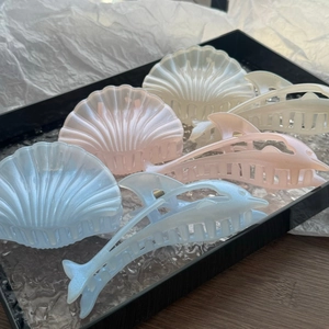 Close-up of dolphin and shell hair claws with pearlescent finish in pastel blue and pink