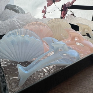 Detail view of pearl-finished dolphin tail hair claws in soft blue and pink colors