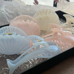 Close-up of pearlescent shell and geometric hair claws in blue, pink and ivory