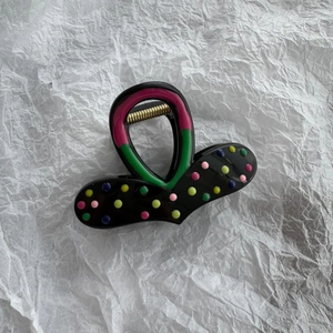 Close-up of heart hair claw clip featuring colorful polka dots and a golden spring