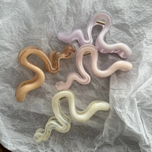 Detail view of wavy hair claws in lavender, amber, pink, and yellow translucent resin