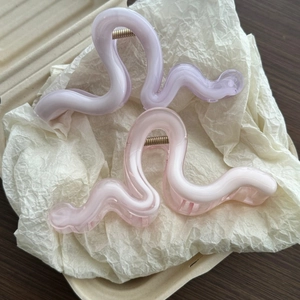 Detail showing wavy pastel purple and pink hair claw clips with smooth glossy finish