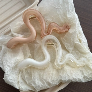 Detail of S-shaped wavy hair claws in translucent cream and dusty pink resin