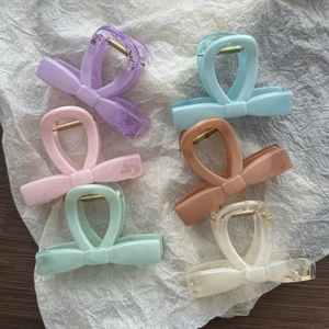 Flat lay of six colorful marble pattern bow hair claws on a white textured background