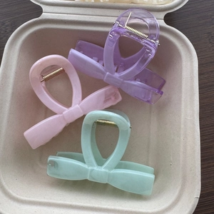 Detail showing set of three bow-shaped hair claws in lilac, pink, and mint green colors