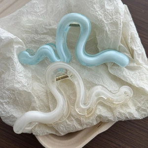 Detail of wavy textured hair claws in translucent blue and marbled white finish