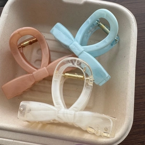 Detailed macro view of three marble-patterned bow hair clips in pastel colors