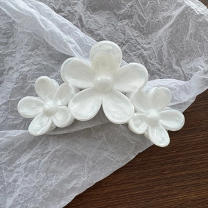 Detail of three white pearlescent flowers hair claw clip with elegant shell-like finish