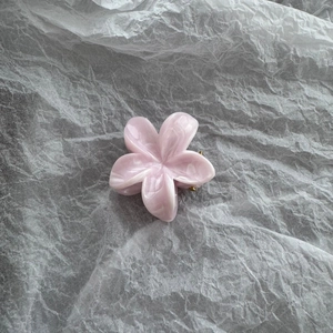 Detail view of a pink marble-textured frangipani hair claw clip with gold metal grip