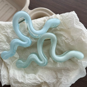 Detail of light blue wavy hair claw clips with translucent texture and silver metal spring