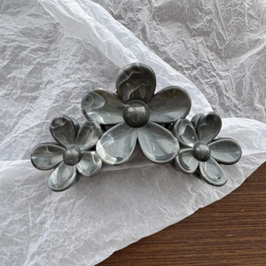 Macro detail of the elegant pearlescent floral hair claw clip on a stylish white tissue