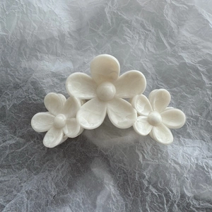 Close-up of three white camellia flowers hair clip with a pearlescent acetate finish