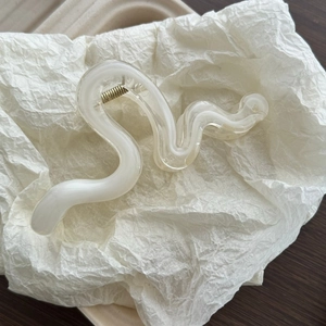 Macro view of creamy translucent wave hair claw clip with golden metal spring
