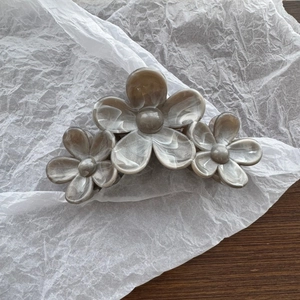 Detail view of large marble texture flower hair claw clip on a soft white paper background