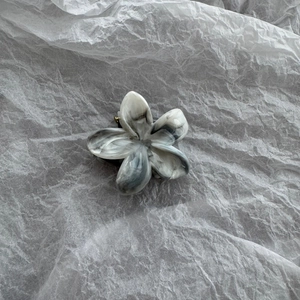 Macro shot of marble textured flower hair claw clip with grey acetate finish and metal spring