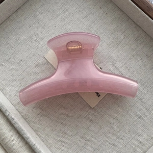 Detalle de la pinza para el cabello en resina nacarada rosa con muelle de metal dorado