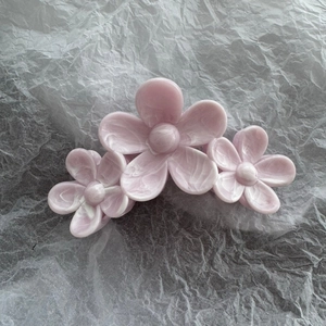 Detail of light pink marble texture acrylic hair claw with triple floral design