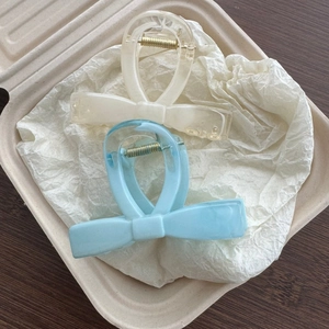 Detail of elegant marble-patterned bow hair claws in cream and light blue resin
