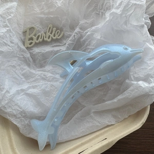 Detailed view of light blue dolphin hair claw clip with glitter finish on white paper