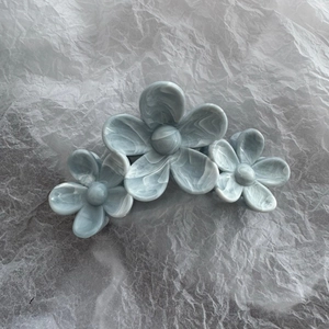 Detail of greyish blue triple flower hair claw clip with marble texture and glossy finish