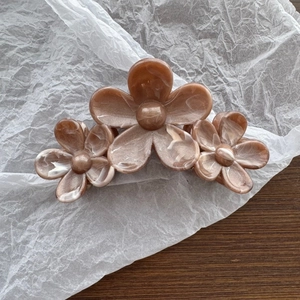 Detail view of pearlescent floral hair claw clip with marble resin texture on white paper