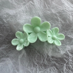 Macro detail of mint green floral hair claw clip with marble texture finish