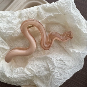 Close-up of wavy translucent jelly orange hair claw clip with golden metal spring
