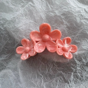 Detail of pink marble pattern camellia hair claw clip with a glossy finish and three flowers
