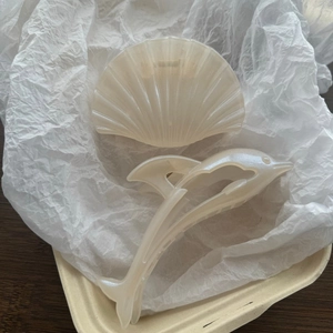 Detailed macro shot of elegant pearlescent dolphin and shell shaped hair claw clips