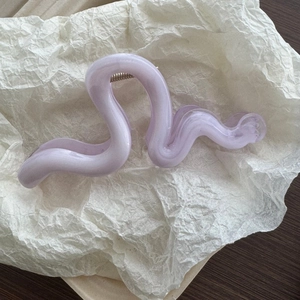 Close-up of translucent lavender water-ripple hair claw clip on white textured paper