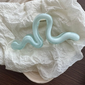 Detail of light green wave hair claw with semi-transparent frosted texture and silver spring