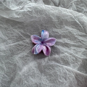 Macro view of purple marble floral hair claw clip with glossy finish on paper