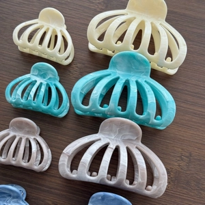 Detail of marble pattern hair claw clips in beige, blue, and pink on wood surface