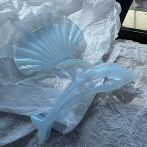 Close-up of sparkling light blue dolphin and shell hair claws on white paper